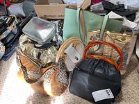 Photo showing various purses on carpet including large brown purse with animal print details, metallic gold handbag and mint green tote.