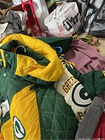 Photo showing green and yellow quilted Green Bay Packers jacket with logo on chest and collar.