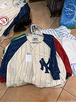 Stack of pinstripe Mirage baseball jerseys on hangers, visible team logos including Yankees and others