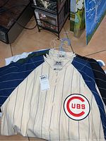 Off-white pinstripe Chicago Cubs jersey with navy sleeves and red Cubs patch on chest, button front, Mirage label