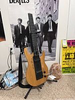 Full view of Yamaha EZ-EG guitar trainer leaning on stand against Beatles poster backdrop