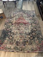 Full view of the Pier One Imports Tapis area rug on wooden flooring with a glass coffee table and furniture visible.