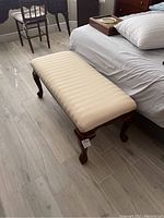 Side view of the wooden end-of-bed bench showing curved legs and cushioned top