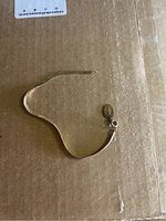 Full view of gold bracelet lying flat showing length and attached religious charm.