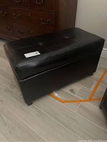 Black leather ottoman with tufted top and storage function