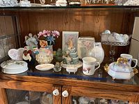 Overall view of the handpainted porcelain decorations and glass decor items displayed in cabinet shelf