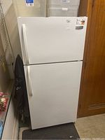 Front view of white Frigidaire refrigerator/freezer, showing top freezer and bottom refrigerator doors with vertical handles.