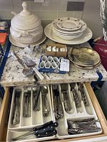 Overall view of porcelain soup server, serving platters, napkin rings, plates, salt and pepper shakers, and silverware drawer.