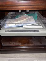 Rotel RP-820 turntable inside a cabinet with dust cover down, original owner’s manual and papers on top of the platter.
