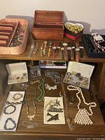 Wooden cedar chest box open with watches in front, assorted necklaces and bracelets on shelf below