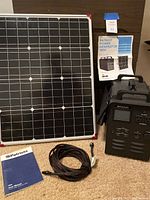 Generator, solar panel, cords and manual arranged for overview
