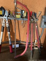 Peg board corner corner showing hacksaw, bolt cutters, and various hand tools hung on rail and peg board.