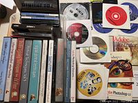 Array of photo editing software CDs and instructional DVDs including Adobe Photoshop, Illustrator, and other digital photography titles.