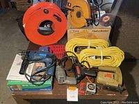 Overview of all power tools laid out on a table including boxed Companion drill, Black & Decker jig saw, circular saw, soldering iron, extension cords and accessories