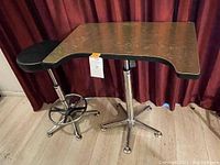 Full view of posing stool with black cushioned seat and posing table with uniquely shaped wooden top on chrome bases.