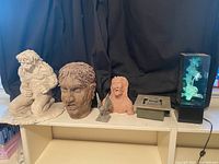 Entire lot of statues and decorative items shown on shelf against black backdrop