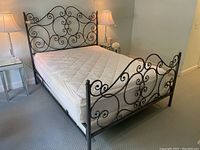 Front left perspective of full-size metal bed with mattress and box spring in bedroom