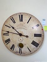 Front view of large, round vintage wall clock with Roman numerals and visible wear