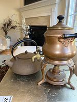 Photo of the teapot and the metal heated dispenser side by side showing details and materials.