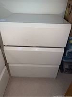 Front view of white 3-drawer night stand with smooth drawer fronts and minor marks
