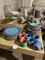 Overall view of pastel ceramic set showing plates, bowls, mugs