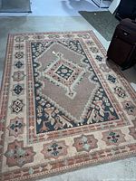 Full view of first rug showing geometric medallion and patterned border on floor.