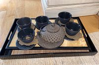 Front view of tea set on black tray showing teapot, four teacups, and tray