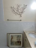 Two framed abstract prints stacked on bathroom counter against wall