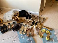 Multiple pairs of women's shoes mostly size 5/6 shown on floor including flats, boots, and sandals in various colors and styles