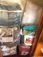 Multiple packaged comforter sets, blankets, pillow and insert in a stack
