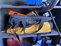 Close view of the black and yellow DeWalt tool bag with zipper open, showing tools inside.