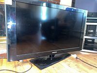 Front view of Samsung flat screen TV on stand, showing screen and frame condition.