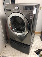 Front view of LG WM3370HAVA front-load washing machine mounted on storage pedestal
