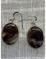 Pair of oval-shaped jasper earrings with 925 sterling silver hook fasteners displayed on textured background.