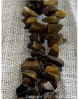 Close-up showing polished tiger eye gemstone chips with distinctive golden brown and dark brown hues.