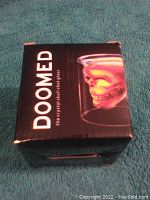 Box of Doomed double wall skull drinking glass with branding visible.