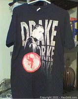 Black Drake t-shirt featuring a large front print of Drake's side profile with repeated text behind and a red circular graphic.