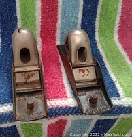 Two Stanley metal hand planes on a multicolored striped fabric, top view showing the blade and marked Stanley brand.