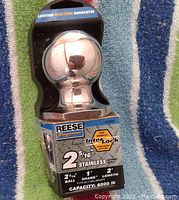 Front view of Reese stainless steel trailer hitch ball in retail packaging with product details visible.