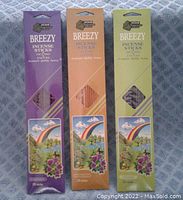 Three packs of Breezy incense sticks in purple, orange, and green boxes showing lavender, sandalwood, and jasmine scents. Each box holds 20 incense sticks.