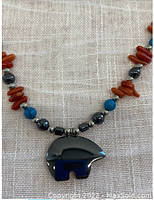 Close-up of the hematite bear pendant and bead details showing turquoise howlite, hematite, ocean shell, and silver spacer beads.