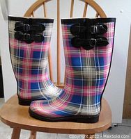 Side view of the plaid rain boots highlighting the double buckle straps and overall pattern.