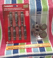 Image showing the packaged 7-piece Husky precision screwdriver set and used wood drill bit set with round handles on a striped towel.