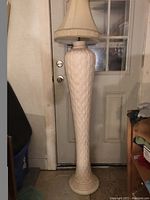 Tall floor lamp with beige textured base and beige fabric lampshade