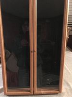 Front view of the display cabinet showing two closed glass doors with wooden frames and knobs.