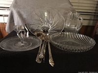 Photo showing heavy glass bowl set with different serving bowls, utensils, and a pitcher arranged on a table