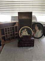 Image showing a vintage wooden printbox with multiple compartments, two oval framed vintage prints of women, and a stack of three antique-style faux book boxes.