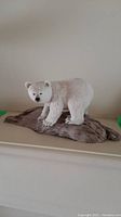 White bear carving on driftwood base, showing front facing view with detailed fur texture and bear expression.