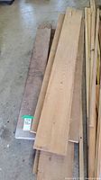 Stack of black walnut and cedar wooden boards showing dark brown and light wood tones with visible grain patterns, laid on the floor.