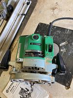 Front view of Hitachi router showing handles, power cord, and attached router bit.
